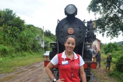 Lysangela (monitora) posa em frete a locomotiva Maria Fumaça, na Estação Manacá